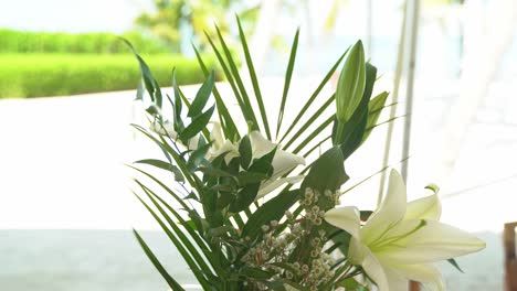 Shot-of-wind-blowing-flowers-wedding-venue-decor-and-flowers-outdoor-seating-sandy-beach-engagement-seating-with-tables