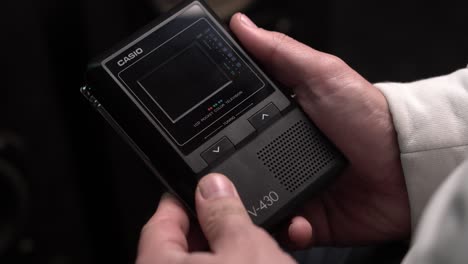 Man-Hand-Holding-Casio-Pocket-TV-Receiver,-Turning-Off-and-Taking-Down-Antenna,-Close-Up