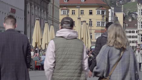 People-enjoying-a-nice-day-in-spring-sitting-and-walking-on-the-town-square,-Marien-Theresien-Strasse-street-in-Innsbruck,-North-Tyrol,-Austria