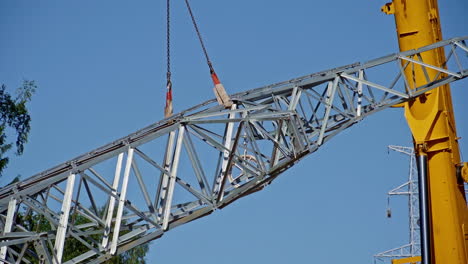 Steel-Cross-Arm-Of-Pylon-Transmission-Tower-Being-Lifted-By-Crane-For-Assembly