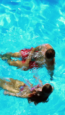 Happy-couple-swimming-in-clear-blue-pool-