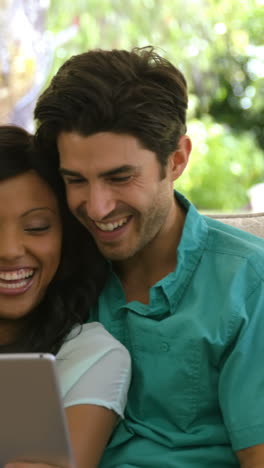 Young-couple-sitting-on-sofa-and-using-digital-tablet-in-living-room