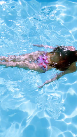 Overhead-of-brunette-swimming-in-pool-on-sunny-day