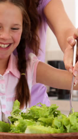 Mother-showing-her-cute-daughter-how-to-toss-a-salad