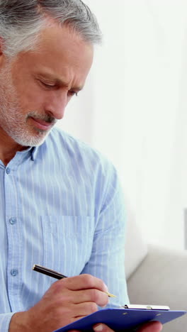 Portrait-of-a-smiling-doctor-writing-notes-on-his-clipboard