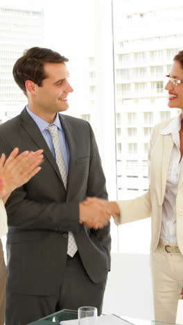 Business-people-shaking-hands-at-interview-while-others-clap