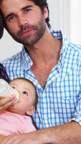 Cute-couple-sitting-on-a-sofa-and-bottle-feeding-to-their-baby