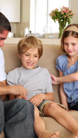 Father-and-daughter-tickling-son-in-the-couch