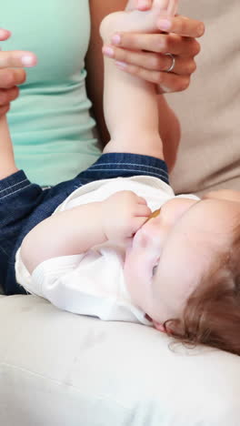 Happy-mother-playing-with-her-baby-son-on-the-couch