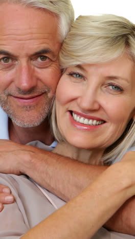 Couple-hugging-on-the-couch-and-smiling-at-camera