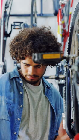 Mechanic-repairing-bicycle-in-workshop