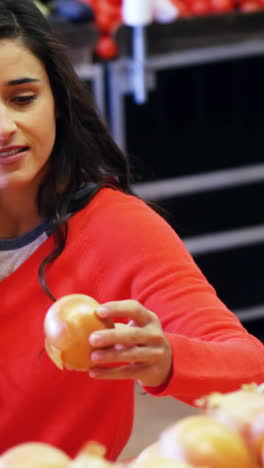 Woman-selecting-vegetable-from-organic-section