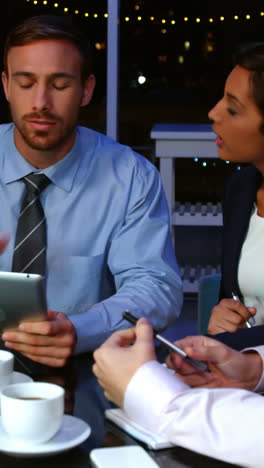 Businesspeople-discussing-over-digital-tablet-in-office