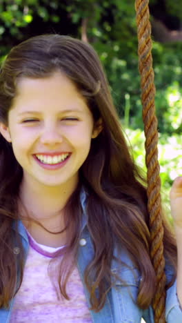 Smiling-little-girl-sitting-on-a-swing-in-the-park