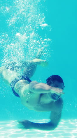 Handsome-man-swimming-towards-camera-underwater