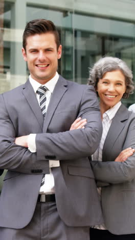 Smiling-Business-people-standing-with-arms-crossed-in-office-building