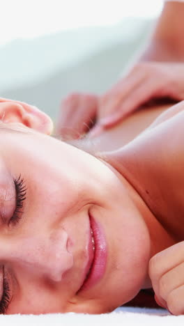 Smiling-brunette-enjoying-a-massage-poolside