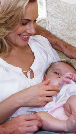 cute-family-sitting-on-a-sofa-and-holding-a-baby