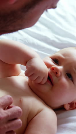 Vater-Spielt-Mit-Seinem-Baby,-Das-Auf-Einem-Bett-Liegt