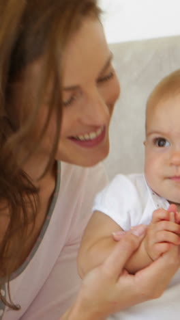 Pretty-mother-playing-with-her-cute-baby-daughter-on-the-bed