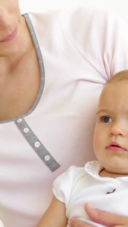 Pretty-young-mother-playing-with-baby-girl-on-the-bed-