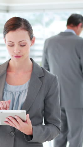 Businesswoman-using-tablet-computer-with-her-colleagues-behind-