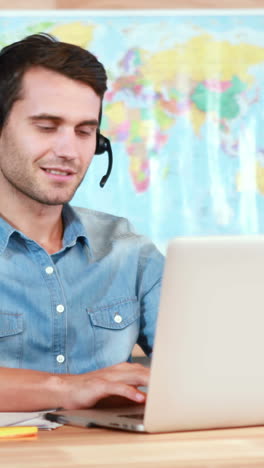 Casual-businessman-using-laptop-and-having-conversation-with-headset