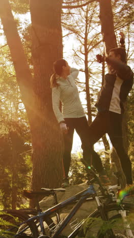 Excited-mountain-biking-couple-standing-on-a-rock