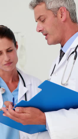 Two-doctors-looking-at-clipboard-in-medical-office