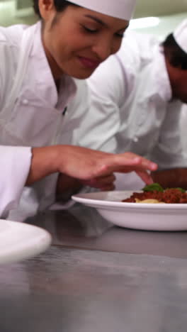 Row-of-chefs-garnishing-spaghetti-dishes