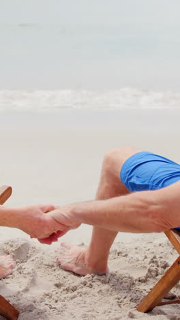 Retired-couple-holding-hands-on-deckchairs