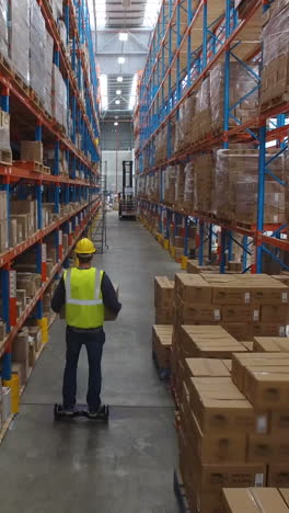 Warehouse-worker-carrying-cardboard-box-on-hoverboard-