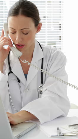 Doctor-talking-on-the-phone-at-her-desk