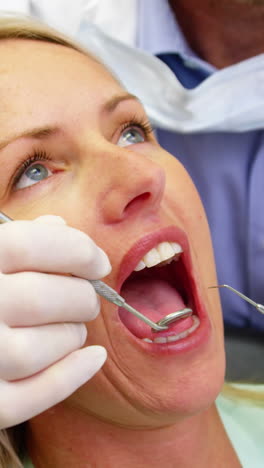 Dentist-examining-a-female-patient-with-dental-tools