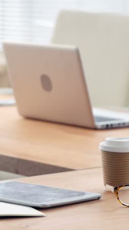 Spectacle,-disposable-coffee-cup,-laptop,-computer-and-digital-tablet-on-desk