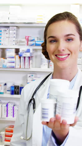 Smiling-pharmacist-showing-medicine-container-in-pharmacy