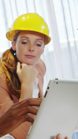 Businesswoman-and-coworkers-discussing-over-digital-tablet