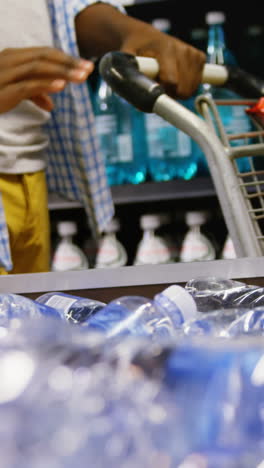 Man-buying-bottle-of-water-at-grocery-section