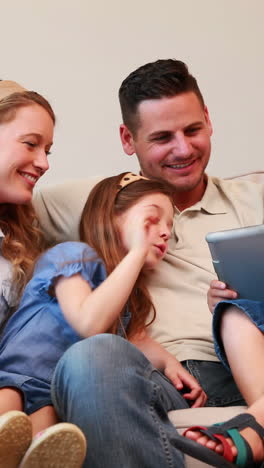 Happy-family-sitting-on-couch-using-tablet-pc