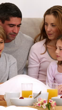 Cute-parents-and-children-having-breakfast-in-bed