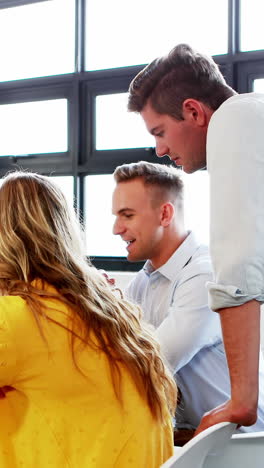 Businesswoman-interacting-with-coworkers-while-working-on-computer