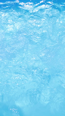 Overhead-of-brunette-swimming-in-pool-on-sunny-day