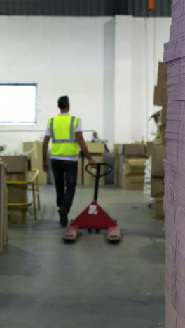 Warehouse-worker-pulling-trolley-away-form-camera