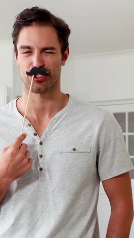 Handsome-man-with-fake-mustaches-making-faces