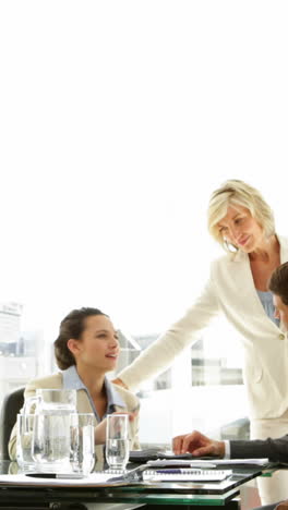 Businessman-leaning-on-desk-with-team-behind-him