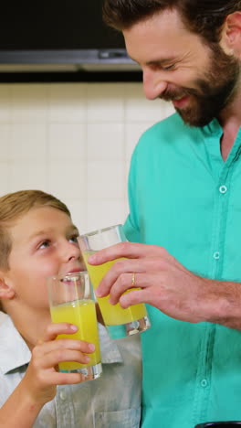 Father-clink-orange-juice-glasses-with-his-son