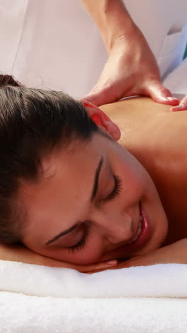 Happy-brunette-enjoying-a-massage-poolside