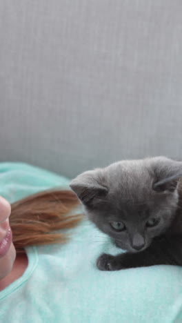 Pretty-woman-lying-on-couch-playing-with-tiny-kitten