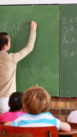 Pretty-teacher-teaching-math-to-her-class-and-smiling-at-camera