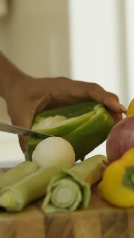 Mid-section-of-woman-chopping-vegetable-in-kitchen